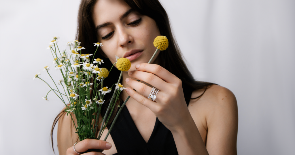 Female model picking flowers while wearing stacked diamond rings.